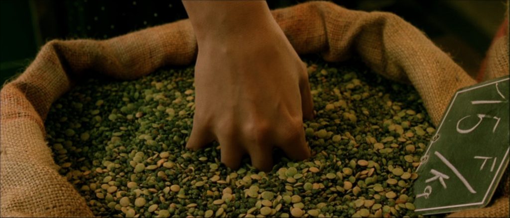 Amélie Poulain plonge sa main au plus profond d'un sac de grains.